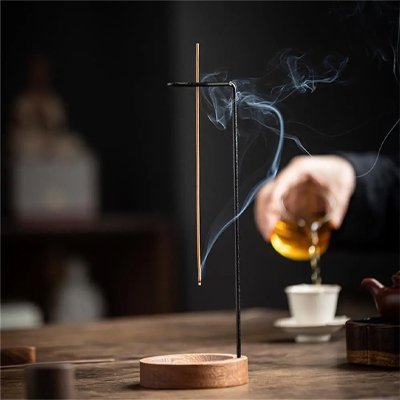 Porte encens avec une main versant du thé